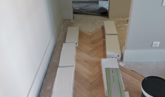 Chantier de pose de parquet en cours avec outils professionnels